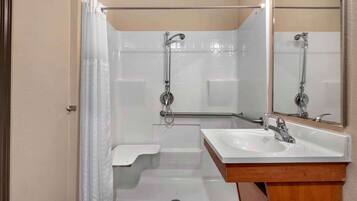 Un baño con lavamanos blanco, espejo y ducha.