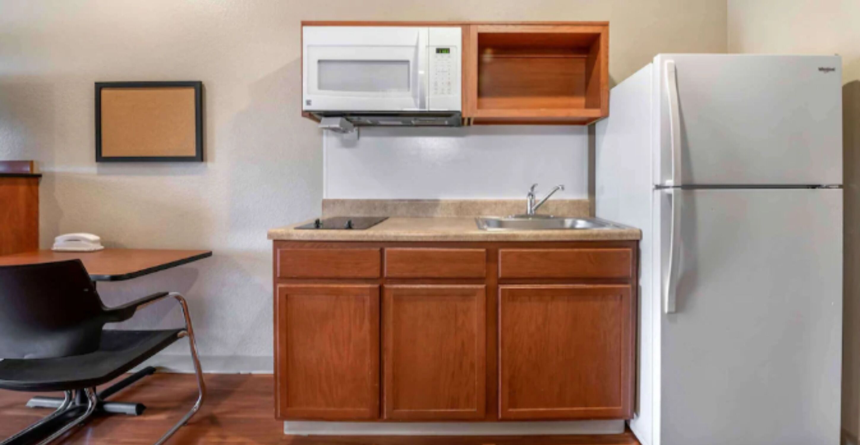 A compact kitchen with a microwave, sink, and refrigerator.