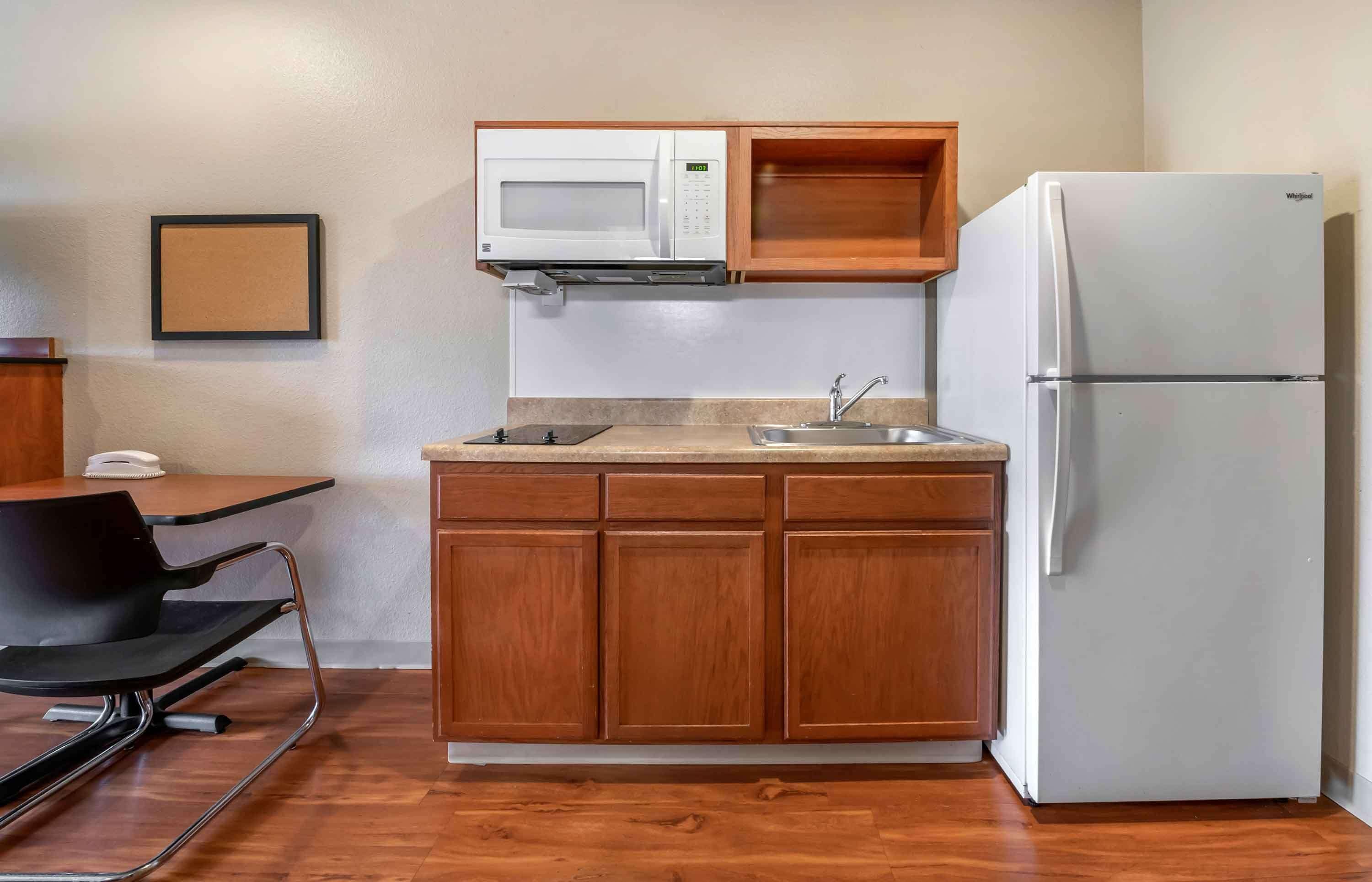 A compact kitchen with wooden cabinets, a white microwave, a sink, and a white refrigerator.