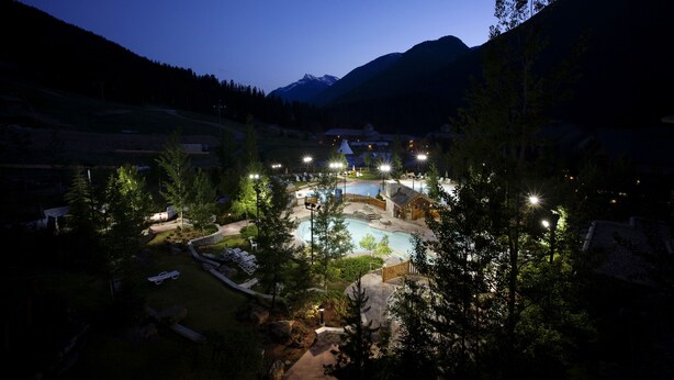 Un resort con piscina, sillas de descanso y montañas al fondo.
