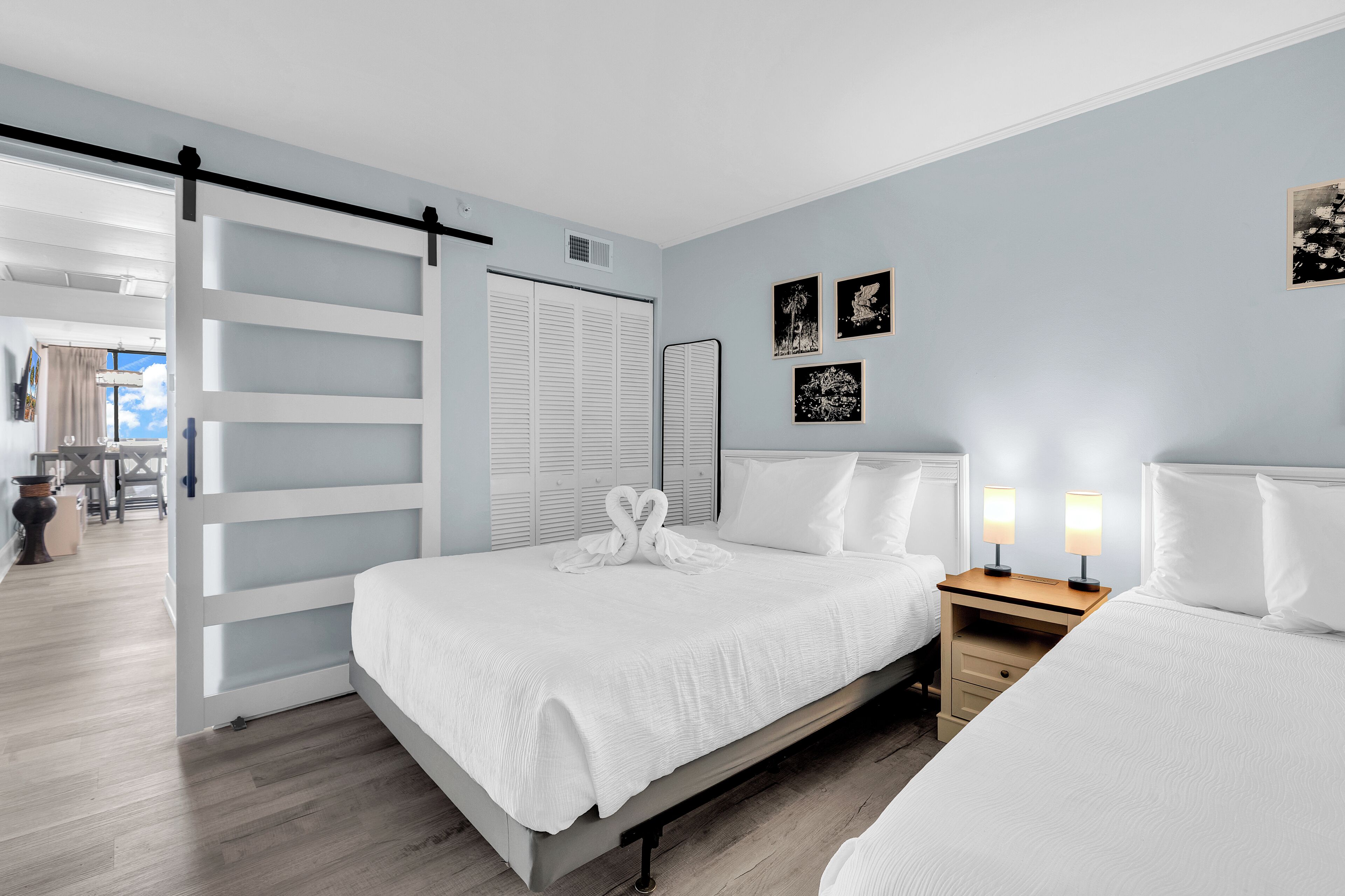 Une chambre à coucher avec un lit, des tables de chevet, une armoire et des œuvres d’art accrochées au mur.