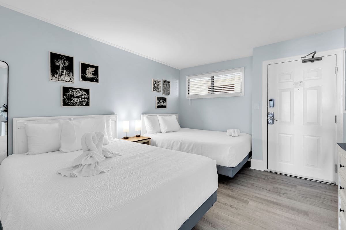 Habitación de hotel con dos camas, una puerta y decoración en la pared.