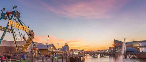 A waterfront amusement park with a Ferris wheel and a water fountain.