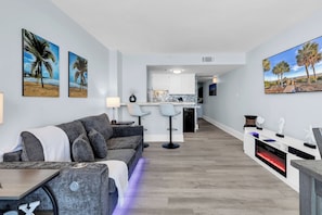 Ein modernes Wohnzimmer mit einer Couch, einem Esstisch und einer Küche im Hintergrund.