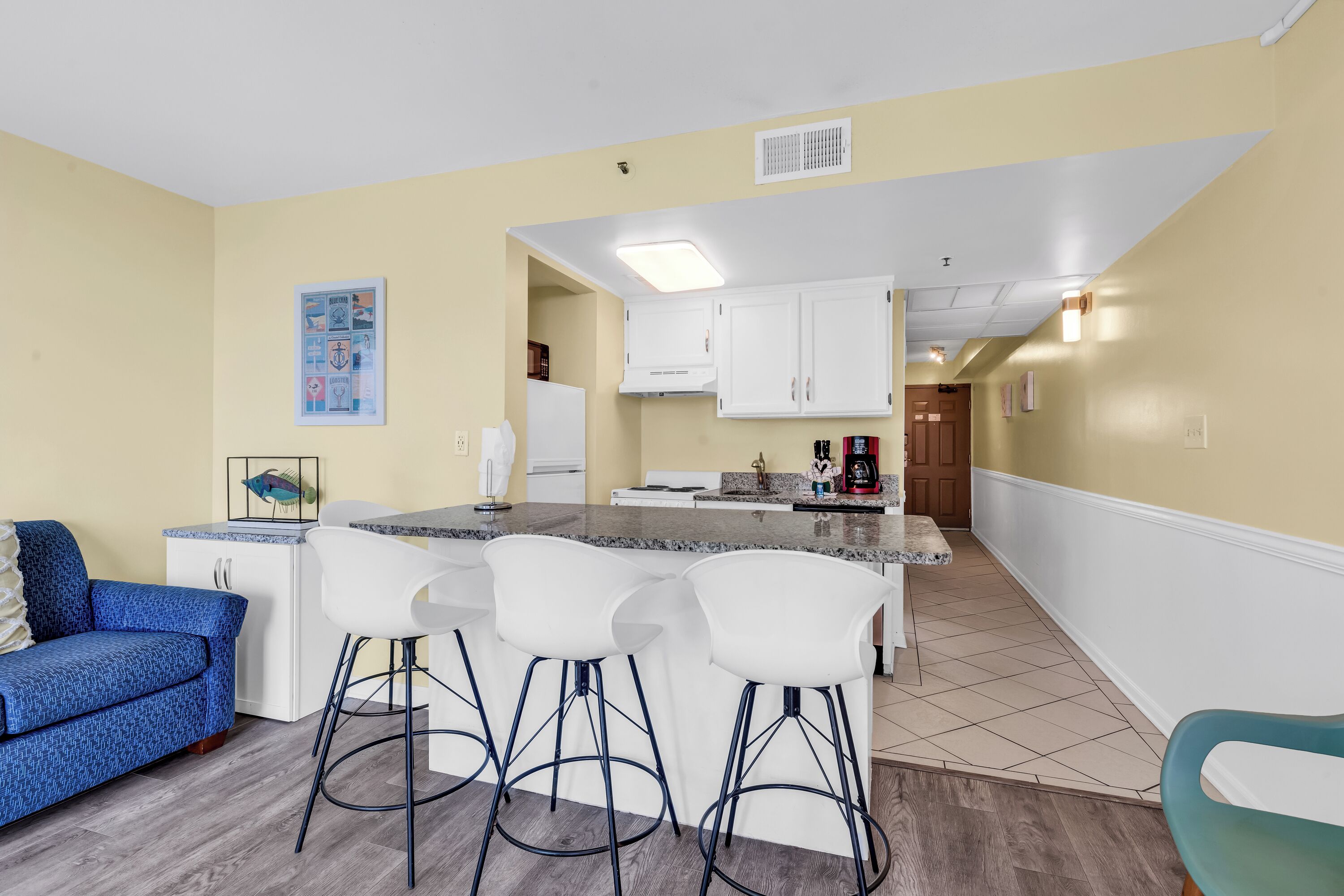 A modern kitchen with white cabinets, a granite countertop, and a built-in island with bar stools.