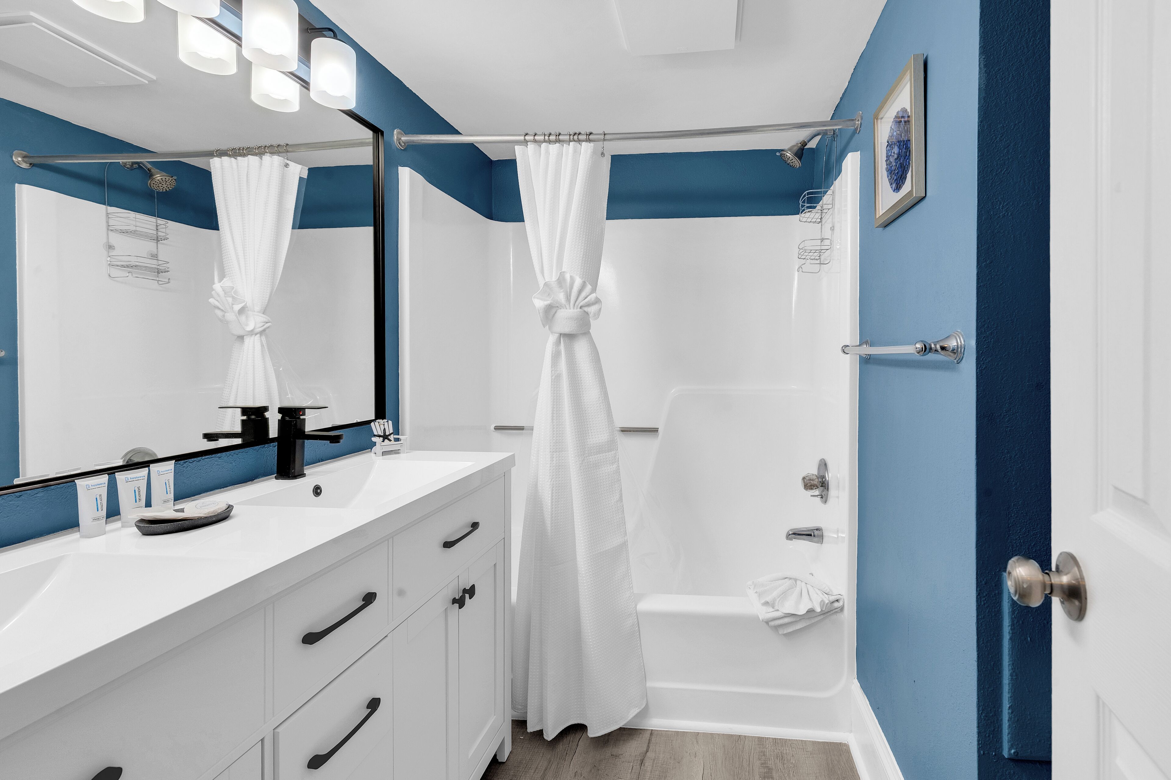 A bathroom with a shower, a sink with a mirror, and a door.
