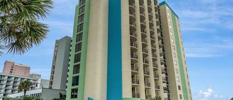 A tall hotel with a green and beige facade, multiple balconies, and a sign indicating it is the Meridian Plaza.