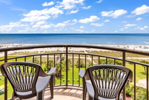 Een balkon met twee stoelen met uitzicht op het strand.