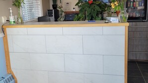 A kitchen with a marble island, a clock, a chandelier, and a refrigerator. - Dockside Inn (Cold Lake)