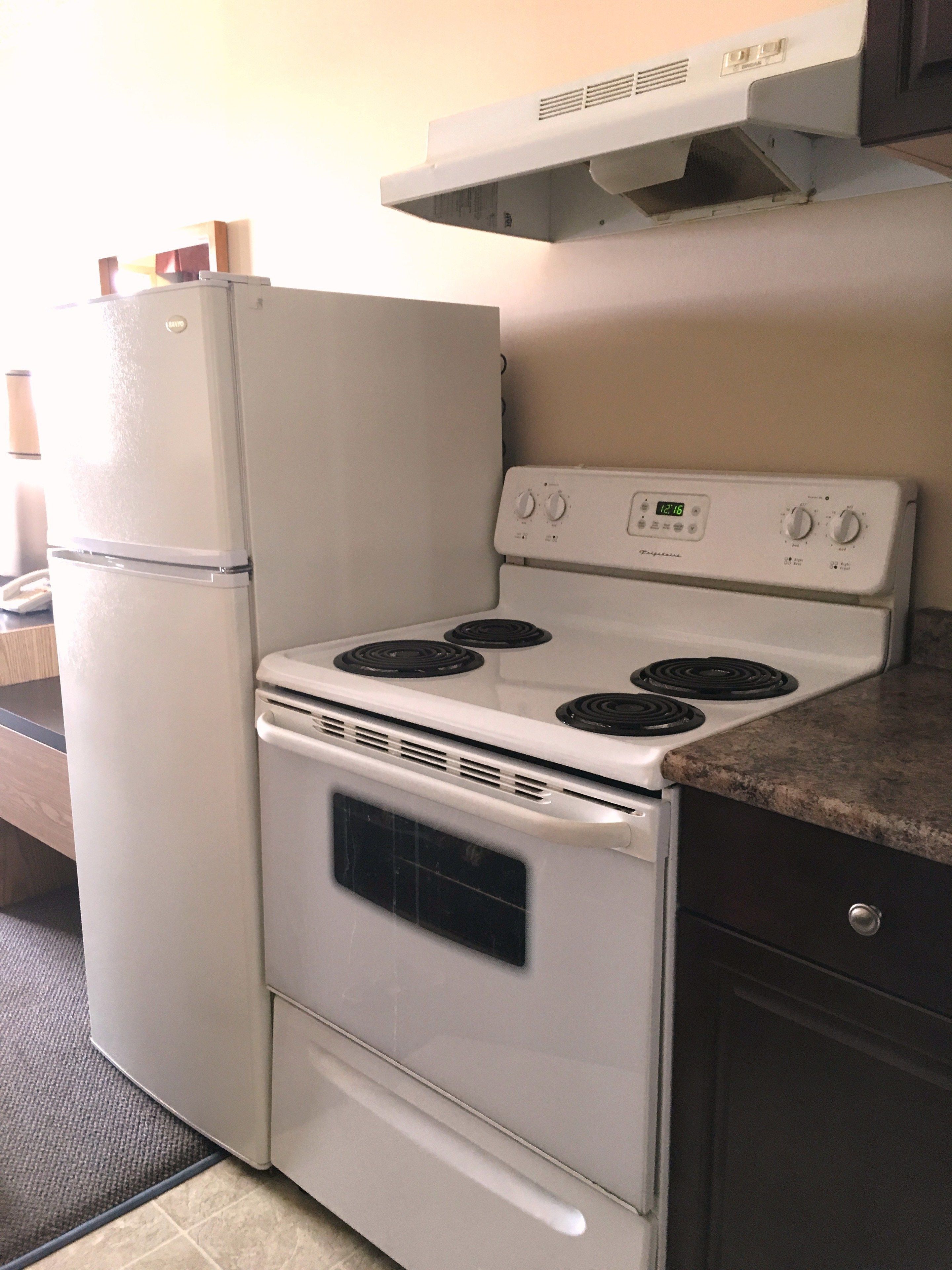 Una cocina compacta con un refrigerador, estufa y horno blancos.