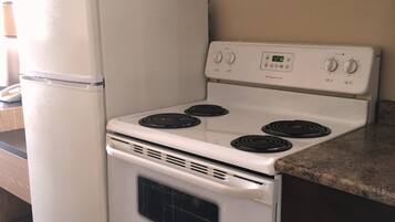 Una cocina compacta con un refrigerador, estufa y horno blancos.