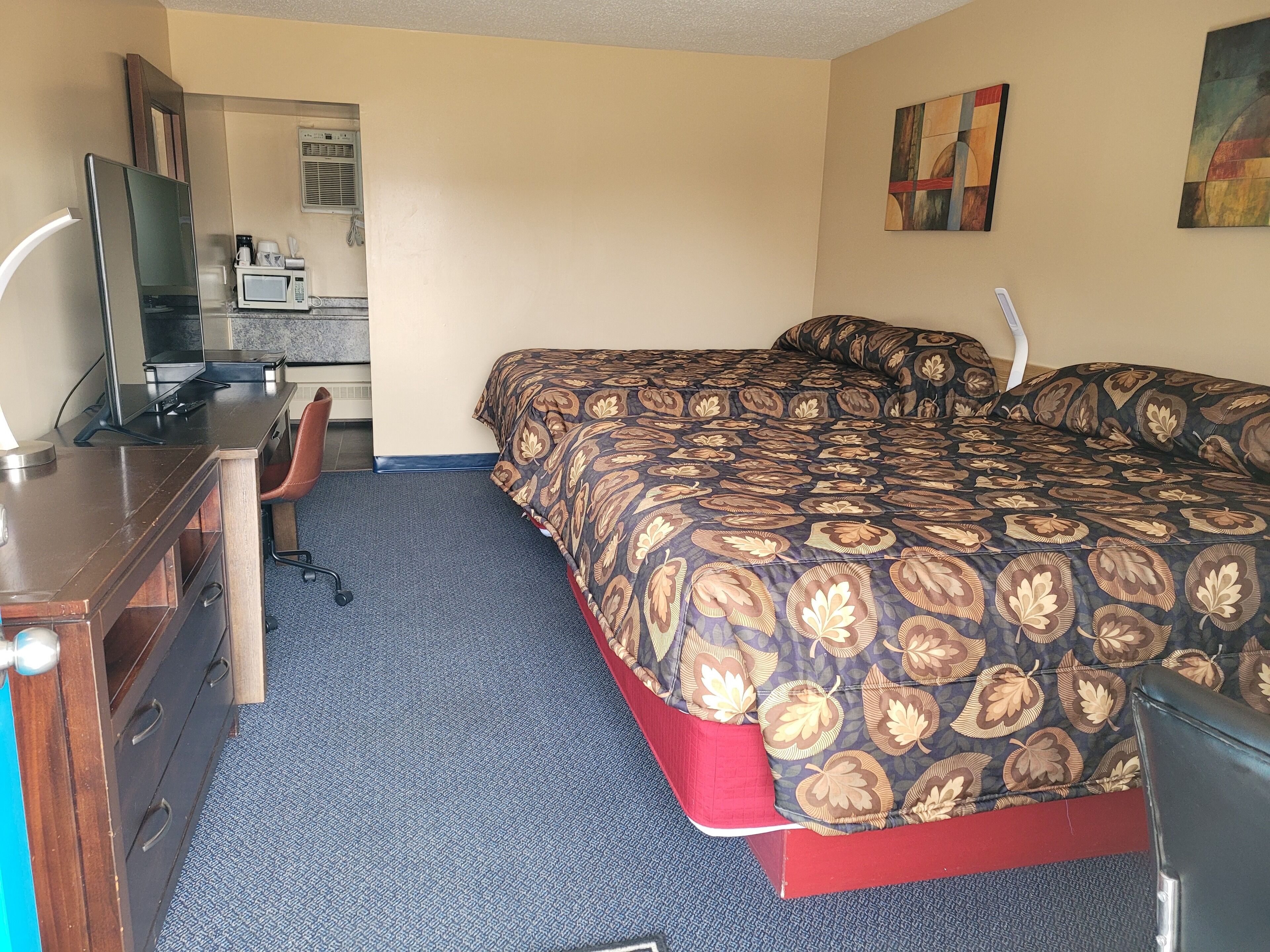 Una habitación de hotel con una cama, un escritorio con una silla, un televisor y un microondas.