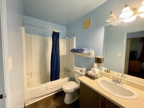 A bathroom with a bathtub, toilet, sink, and a shower curtain.