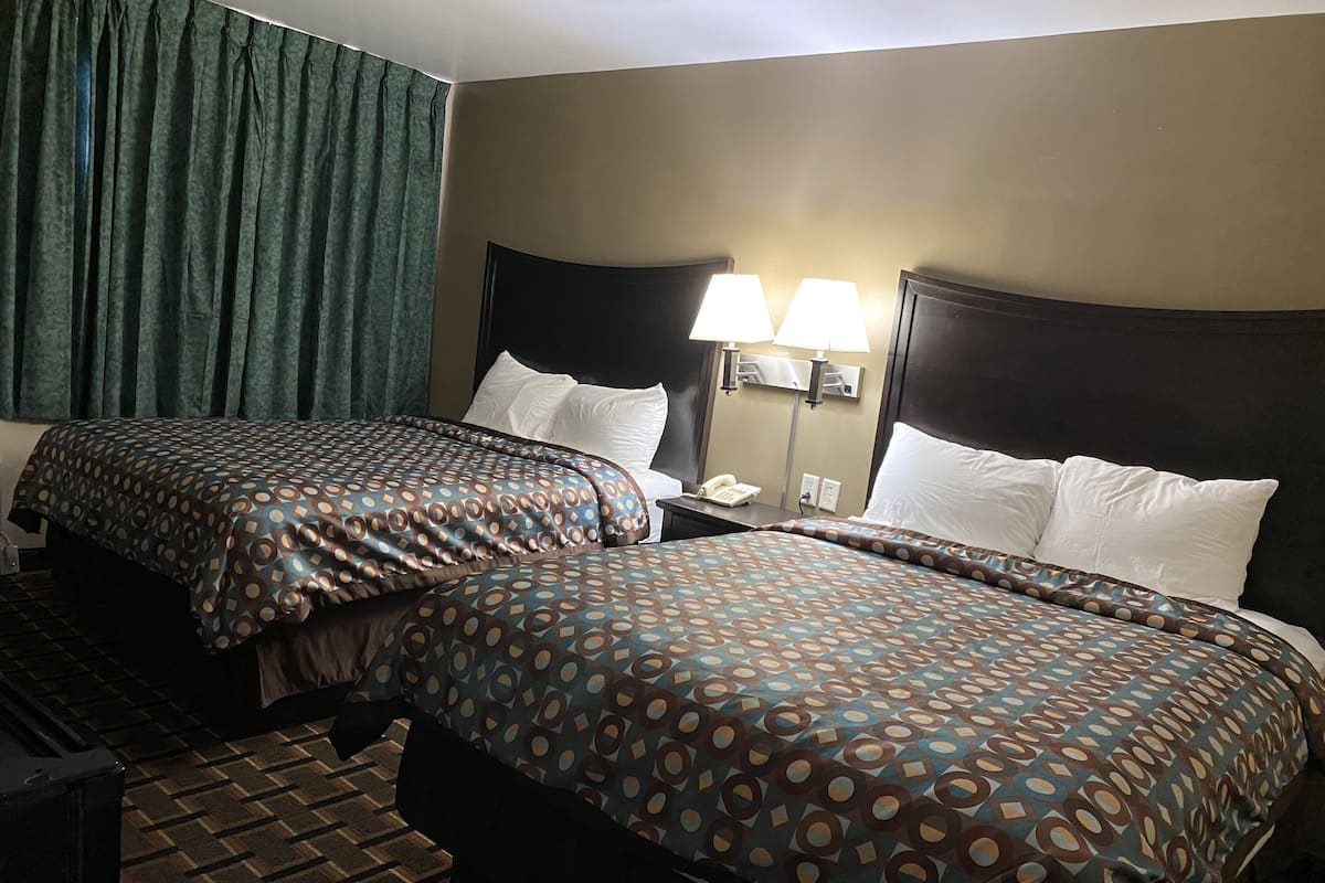 Une chambre d’hôtel avec deux lits, une table de chevet, une lampe et un téléphone.