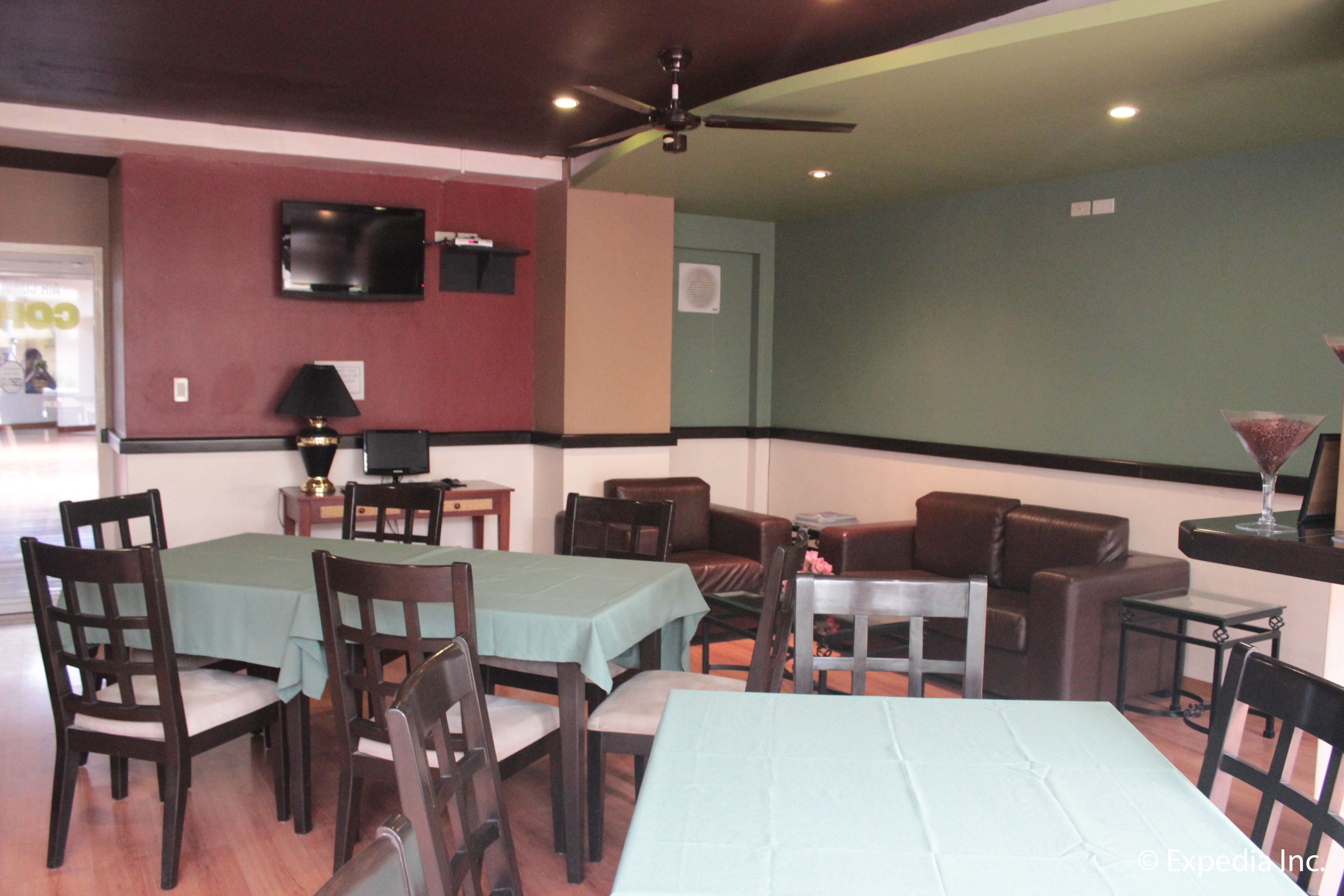 Un espace repas avec des tables et des chaises, un téléviseur fixé au mur et un ventilateur de plafond.