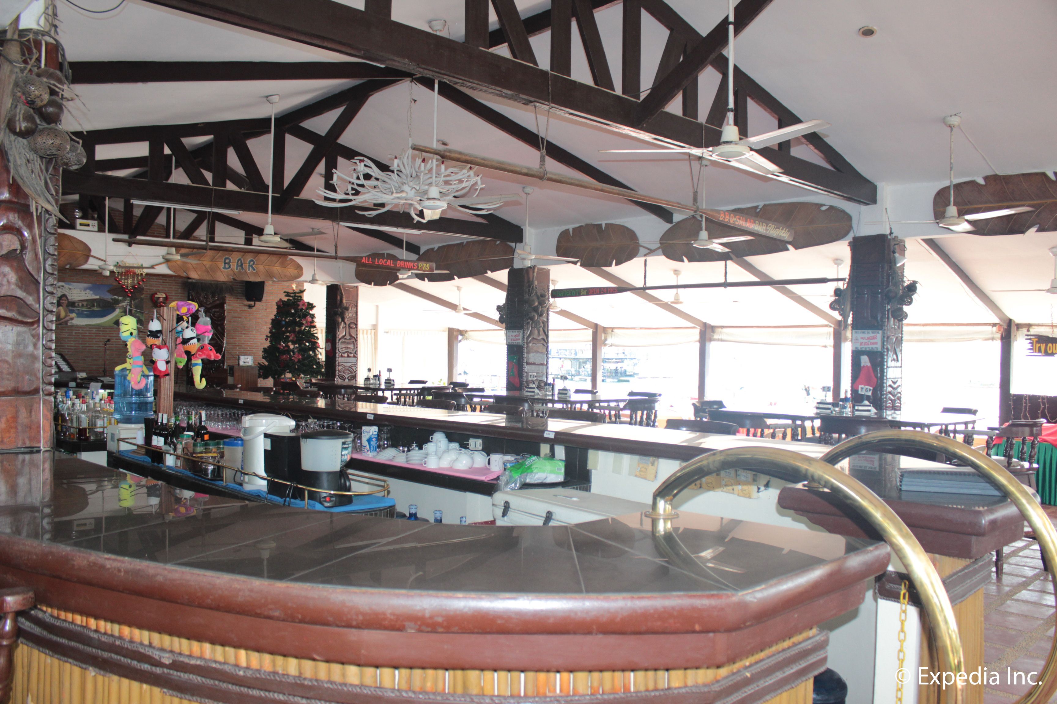 A bar area with wooden beams, a Christmas tree, and a large window.
