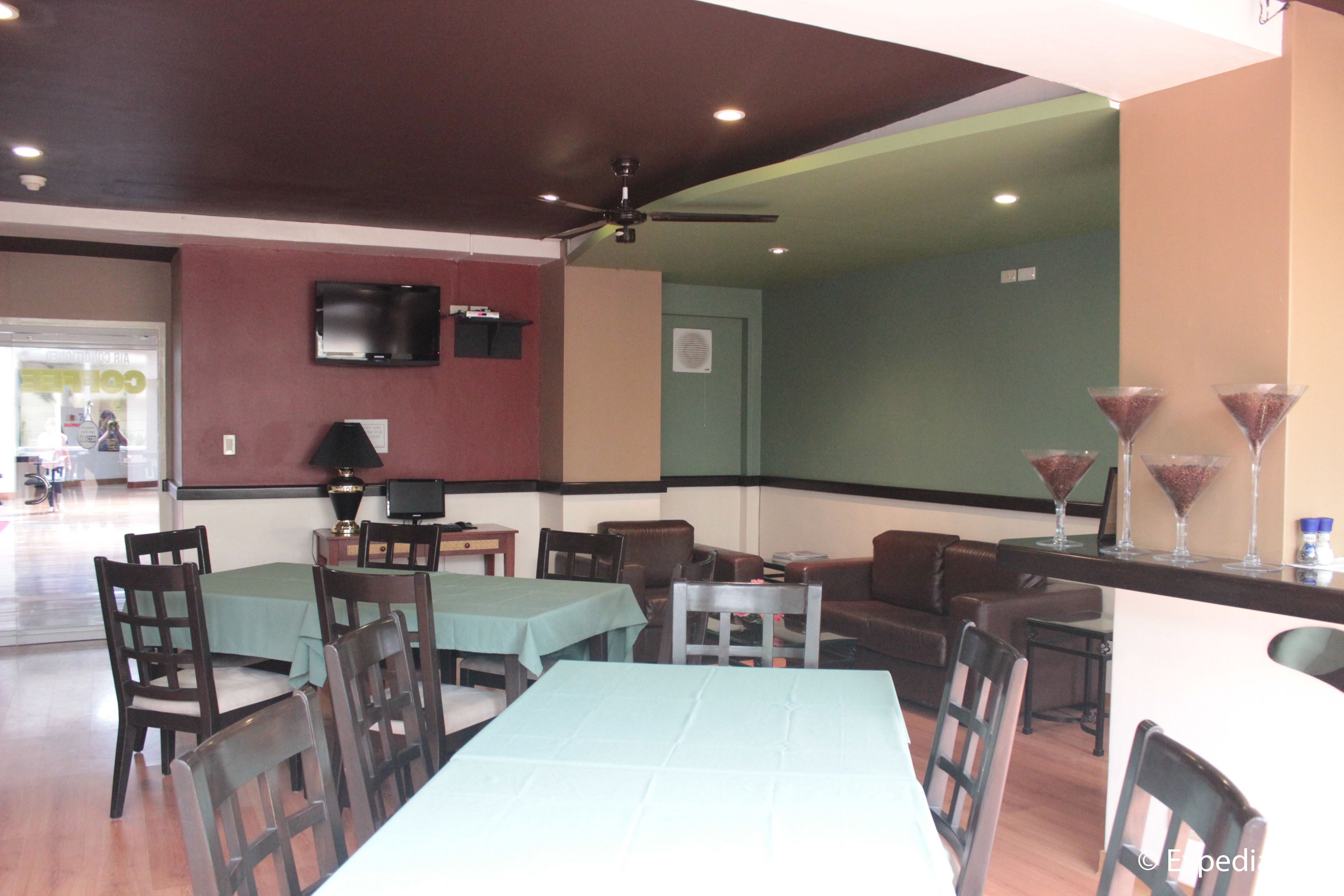 A restaurant with tables and chairs, a television on the wall, and a ceiling fan.
