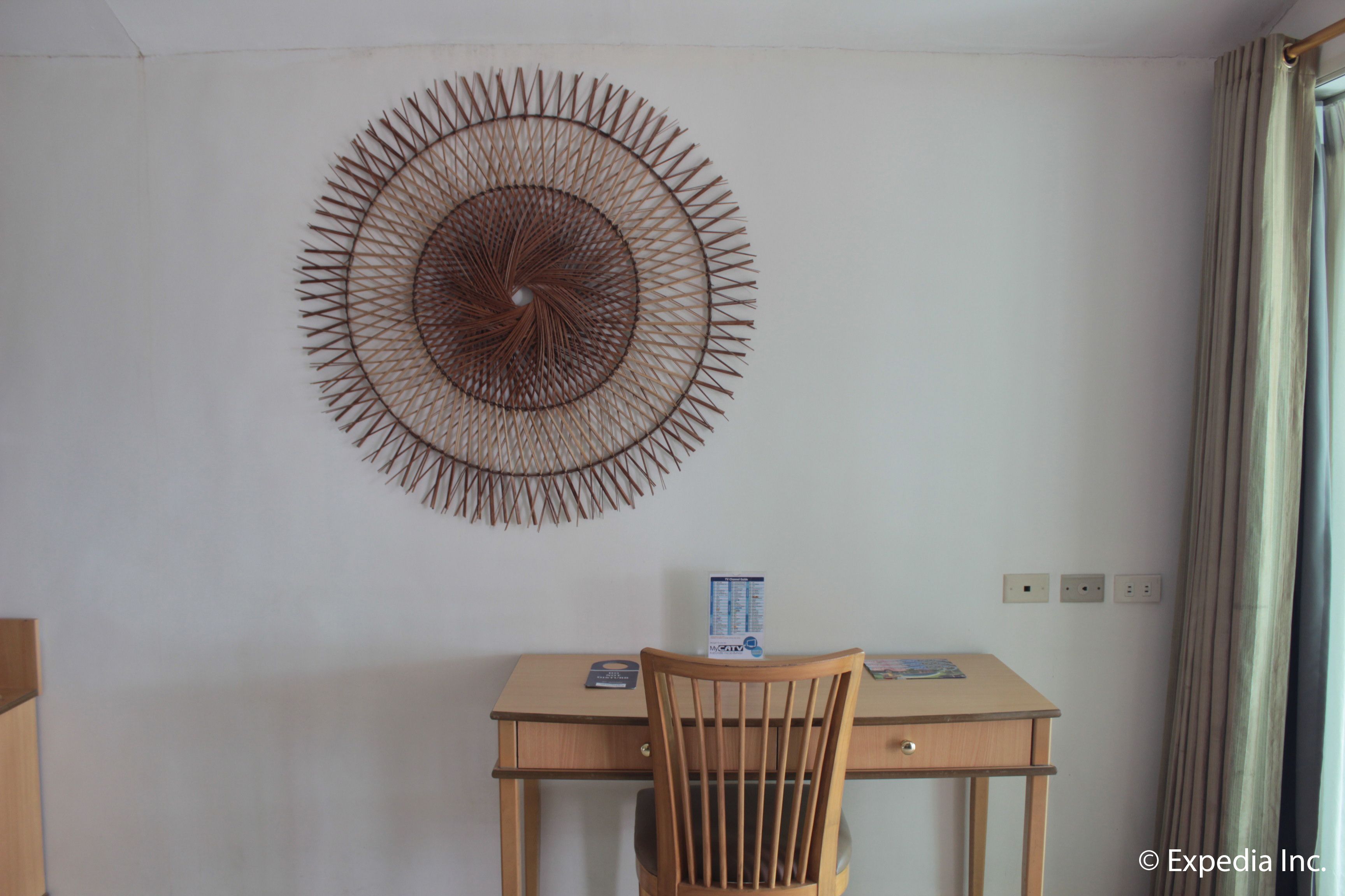 A room with a wooden desk, a chair, and a wall-mounted decorative piece.
