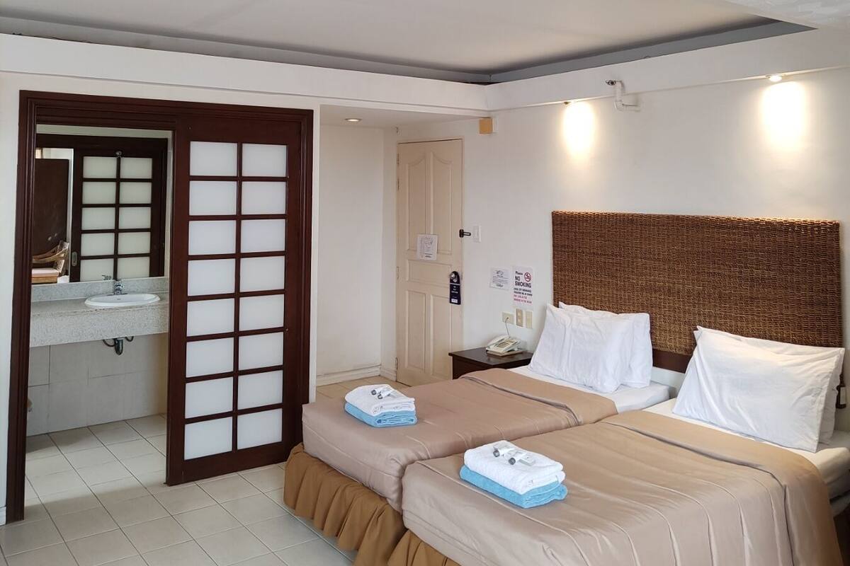 A hotel room with a bed, a bathroom, and a view of the outside.