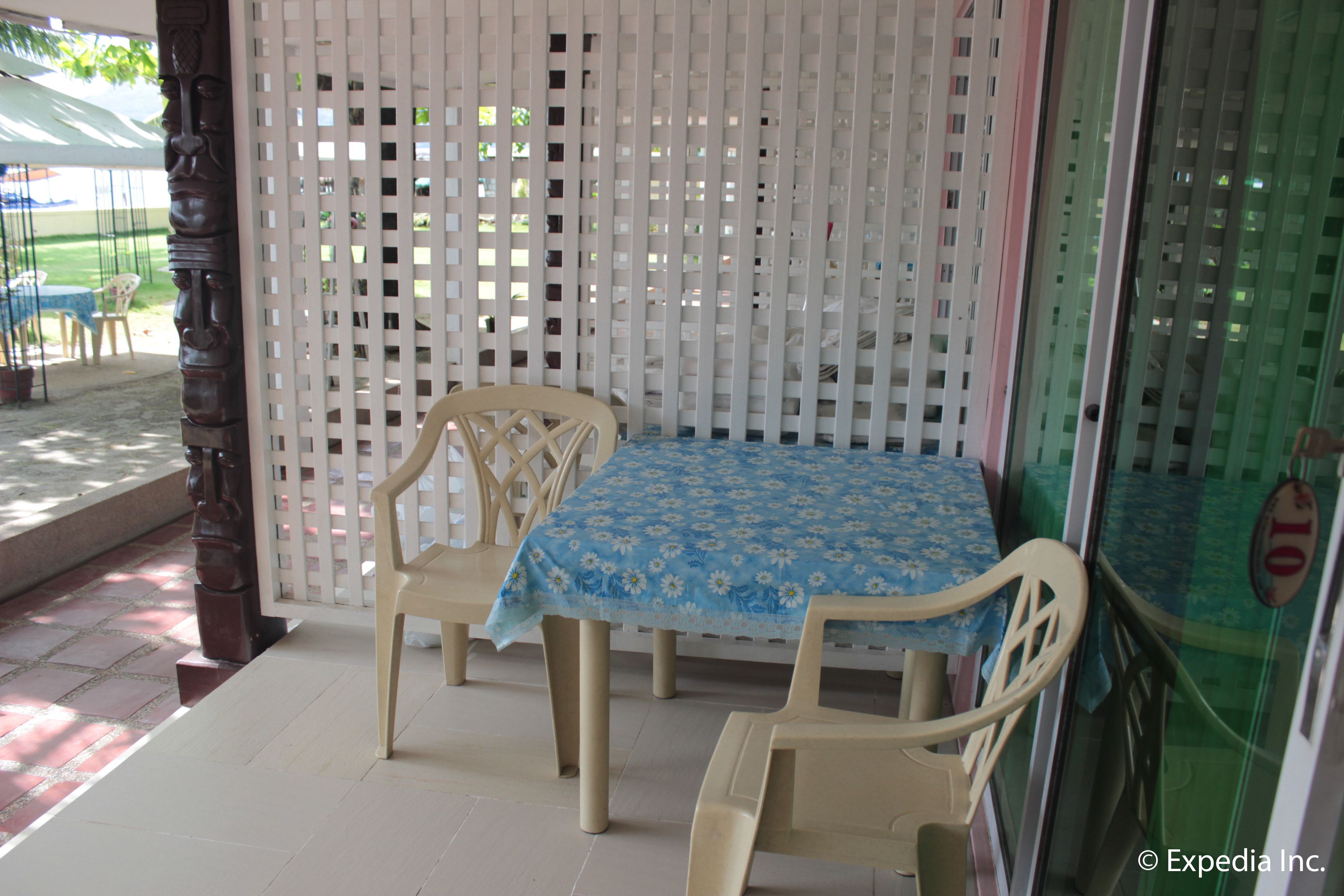 Una habitación con una mesa y dos sillas, una ventana con vista a un edificio, y una puerta con un panel de vidrio.