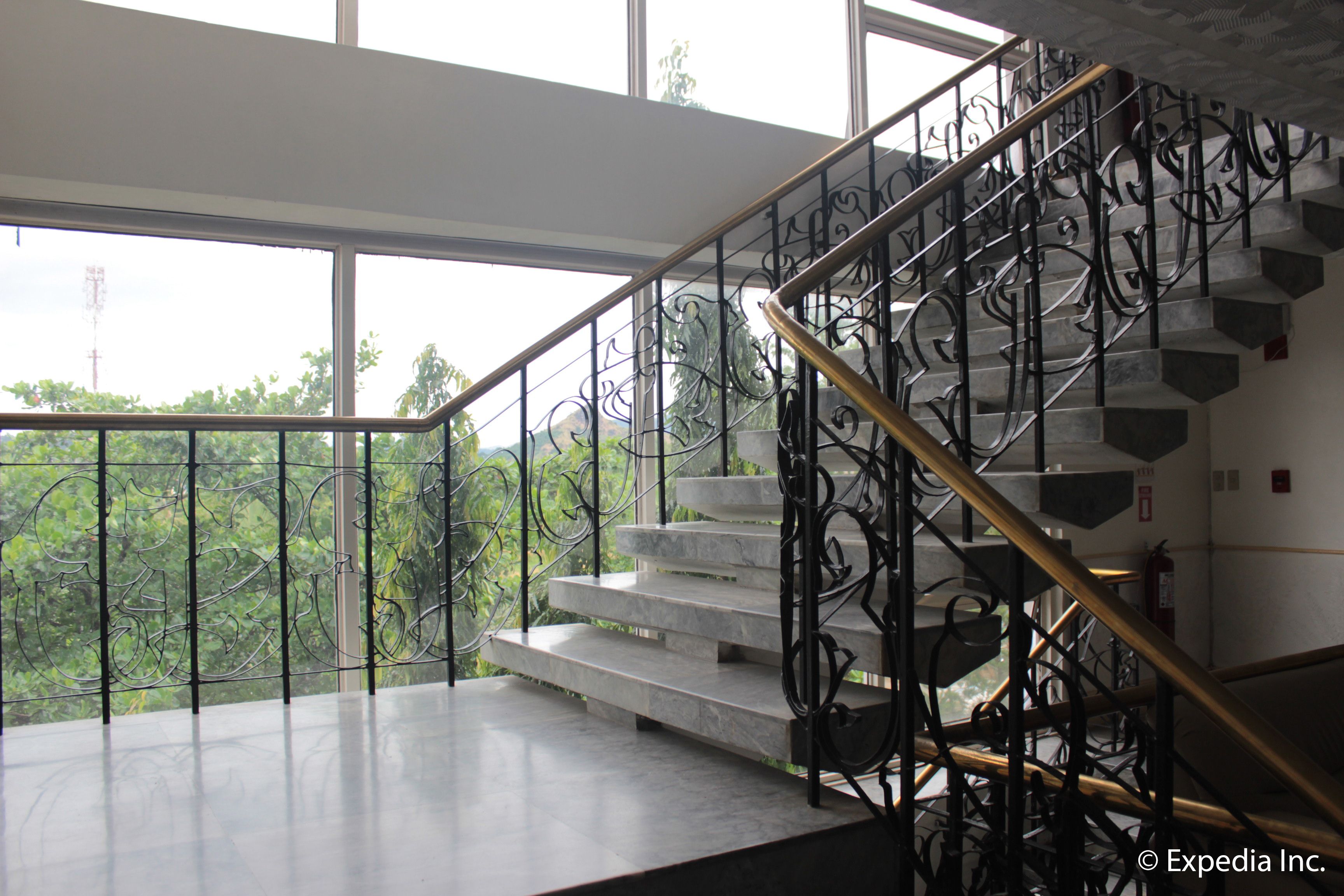 A staircase with ornate metal railings and a glass balustrade, leading to an upper floor.