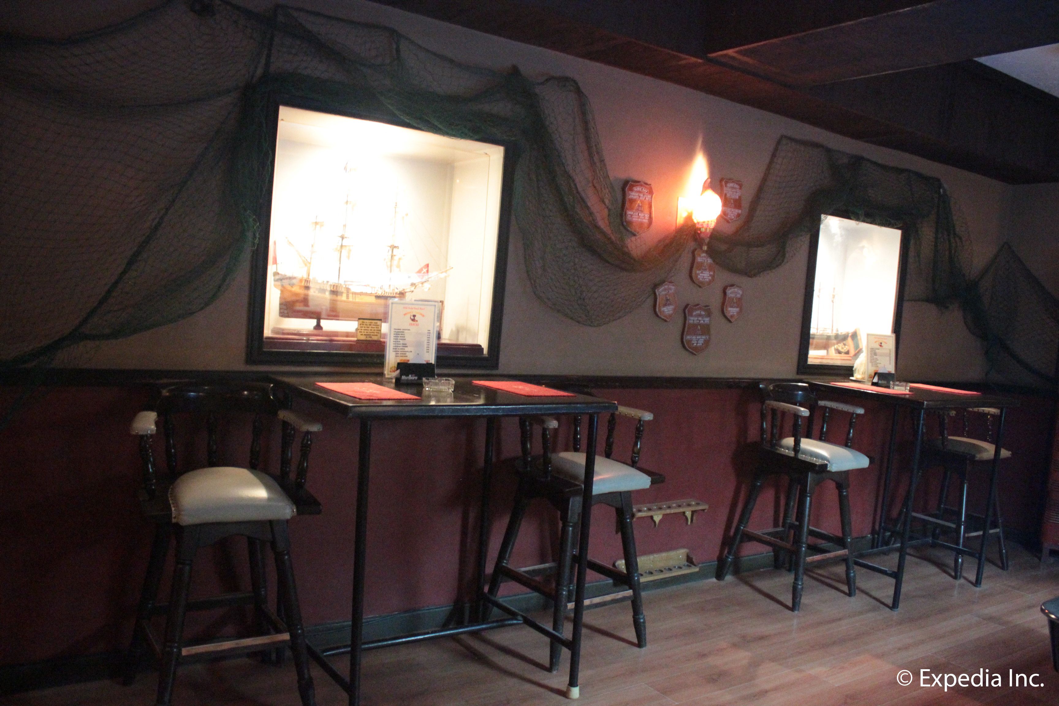 A bar area with two bar stools and a window with a view of a ship.
