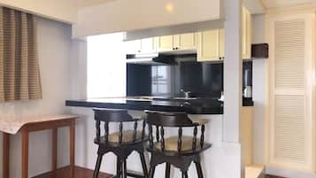 Una cocina moderna con encimeras negras, armarios blancos y estufa integrada. Hay dos taburetes de madera con asientos acolchados.