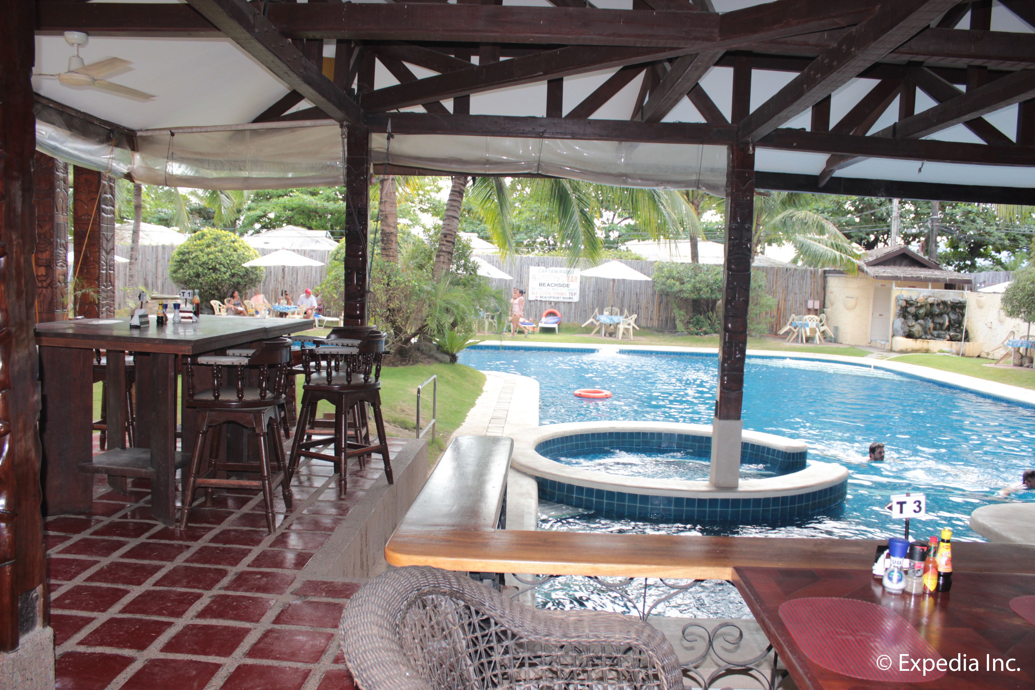 Un espacio al aire libre techado con piscina, bar y mesas.