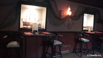 A bar area with a large window displaying a ship, bar stools, and a menu stand.