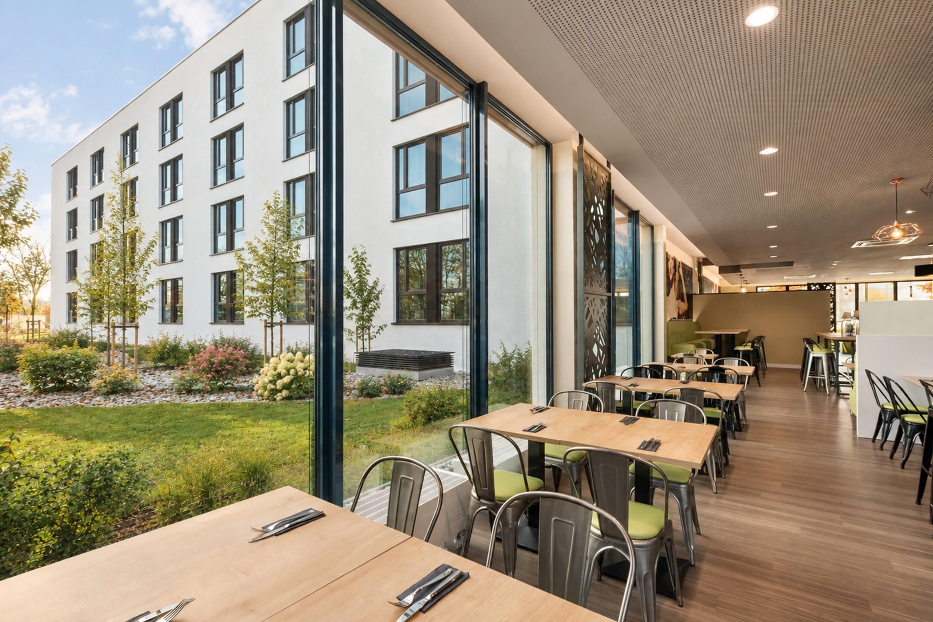 A modern dining area with large windows, a garden view, and a contemporary interior design.
