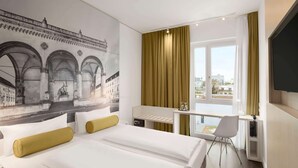 A hotel room with two beds, a desk, a chair, a TV, and a mural of a historical building. - Super 8 by Wyndham Munich City North (Munich)