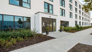 A modern building with multiple windows and a landscaped entrance area. - Super 8 by Wyndham Munich City North (Munich)
