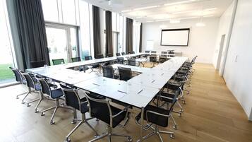 A conference room with a long table, chairs, and a projector screen.