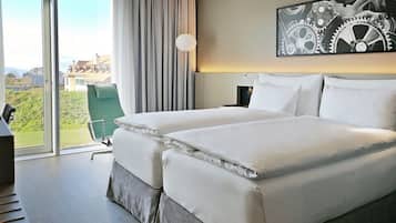 Habitación de hotel con una cama grande, un escritorio, una silla y vistas al exterior.