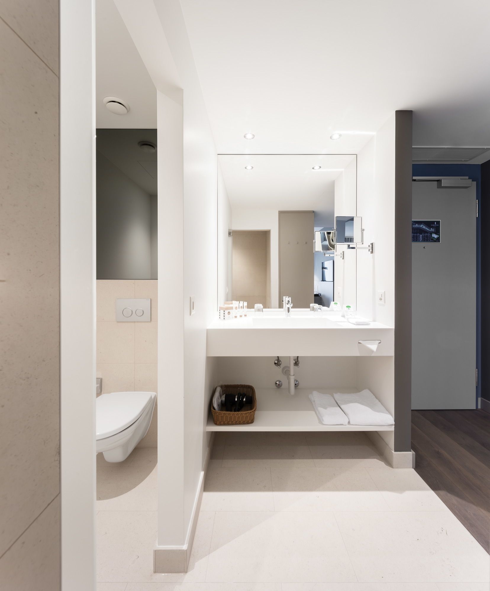 Un baño moderno con lavamanos, espejo y retrete blancos.