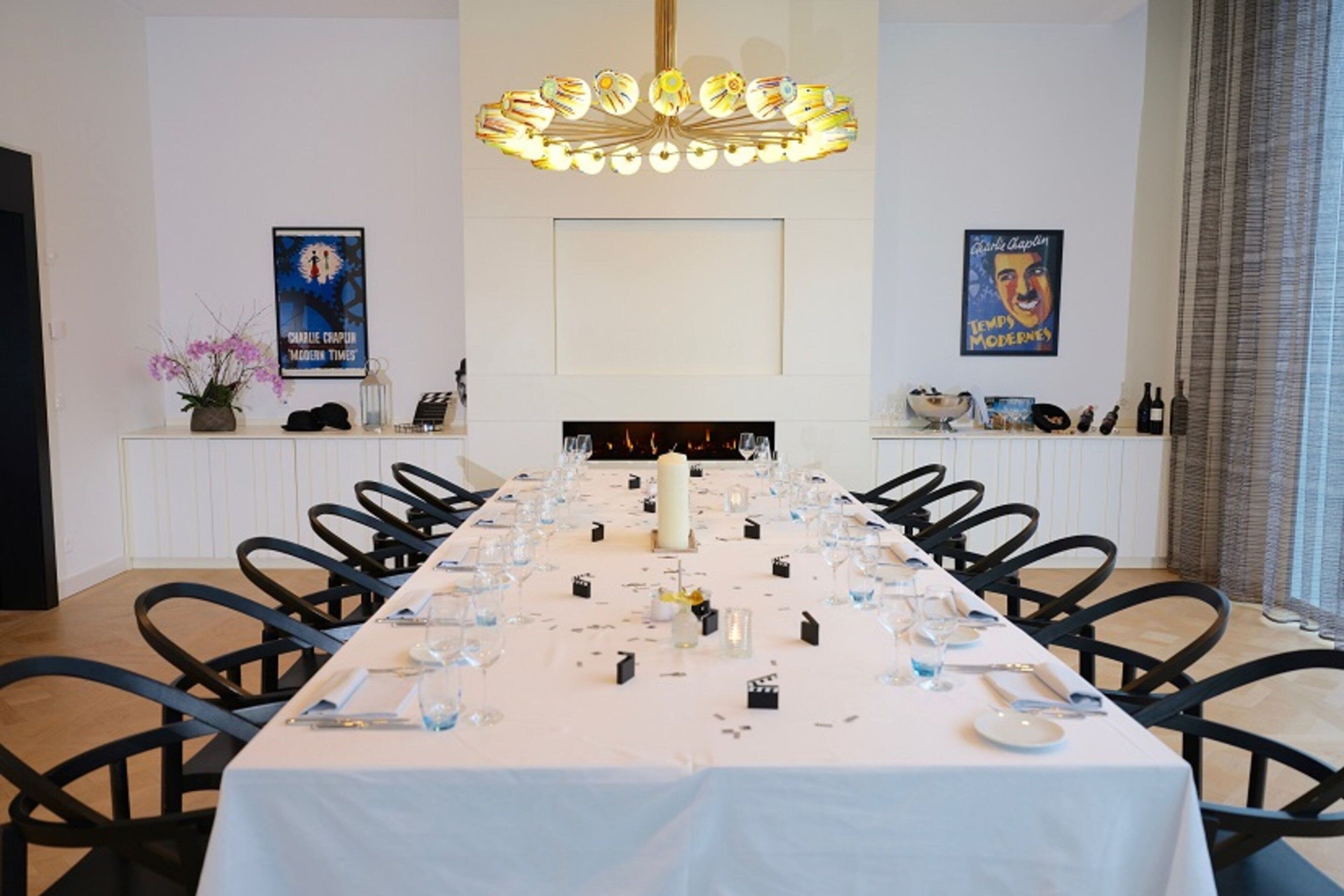 A long dining table set for a meal, with chairs on both sides.