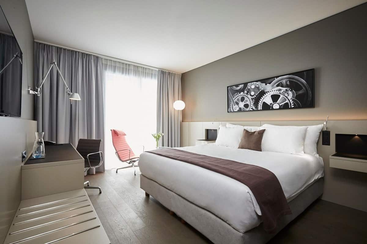 Une chambre d’hôtel moderne équipée d’un grand lit, d’un bureau, d’une chaise et d’une lampe de bureau.