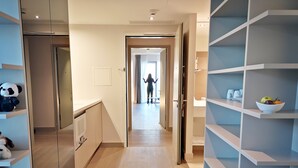 Un pasillo moderno de hotel con vista despejada a una habitación, un pasillo con una persona caminando y un frutero en un estante.