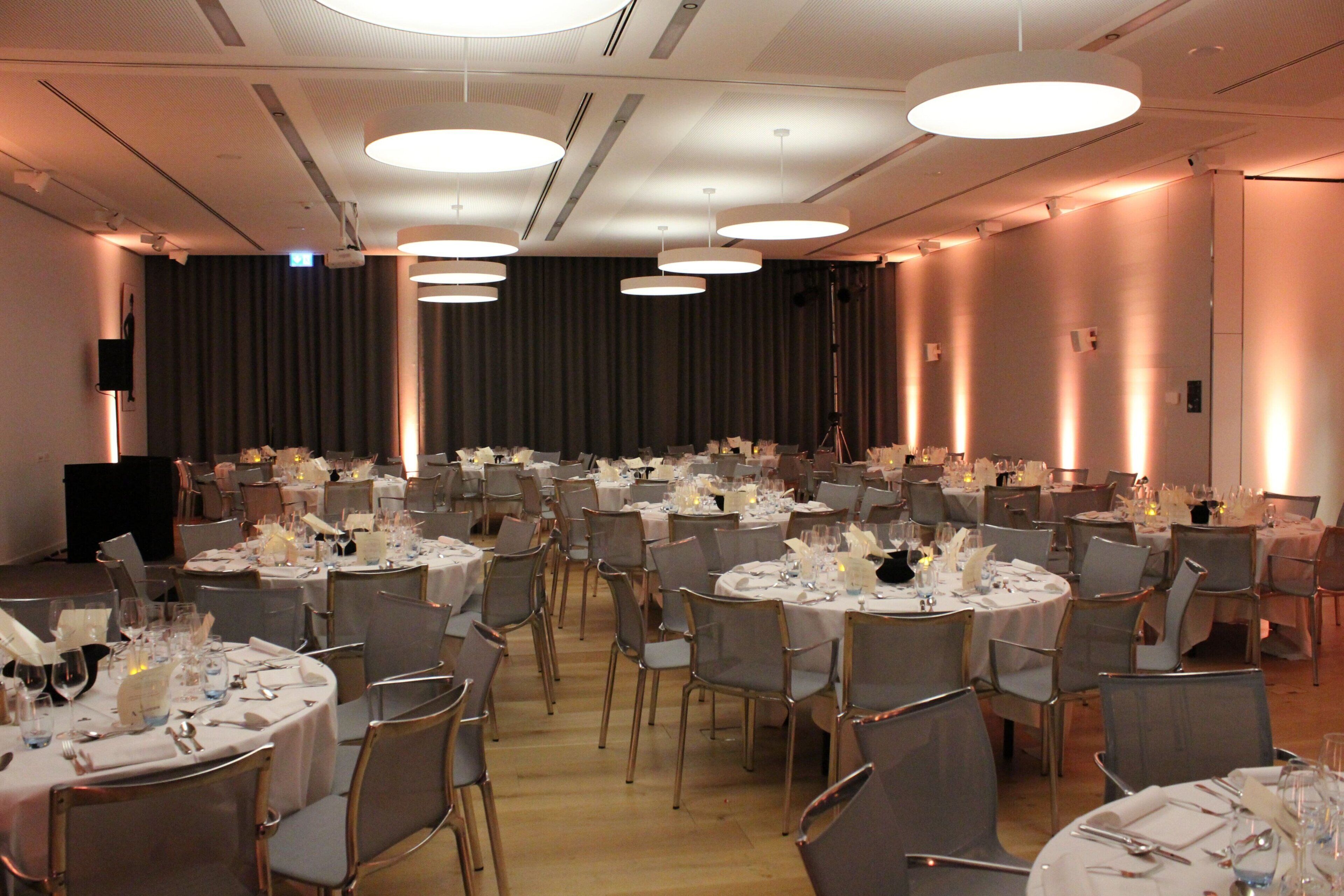 A banquet hall with round tables set for dining, equipped with chairs and table settings.