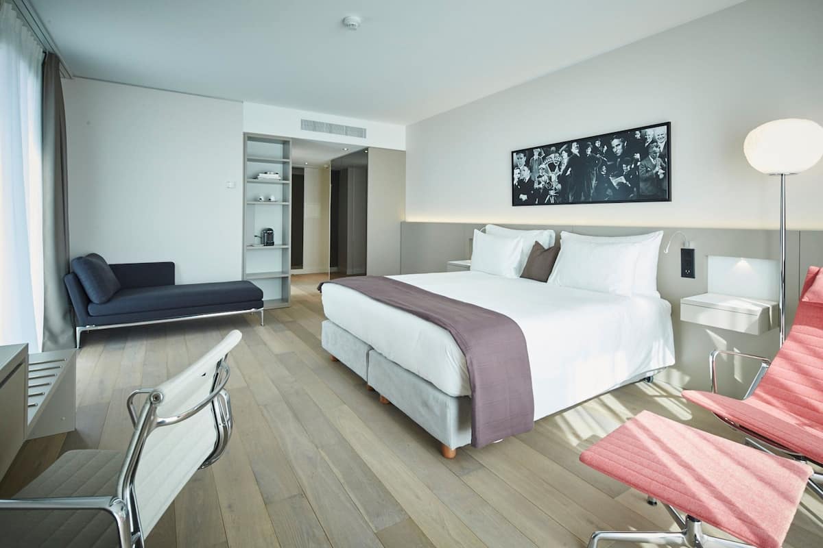 Une chambre d’hôtel moderne, dotée d’un grand lit, d’un bureau, d’une chaise et d’un canapé.