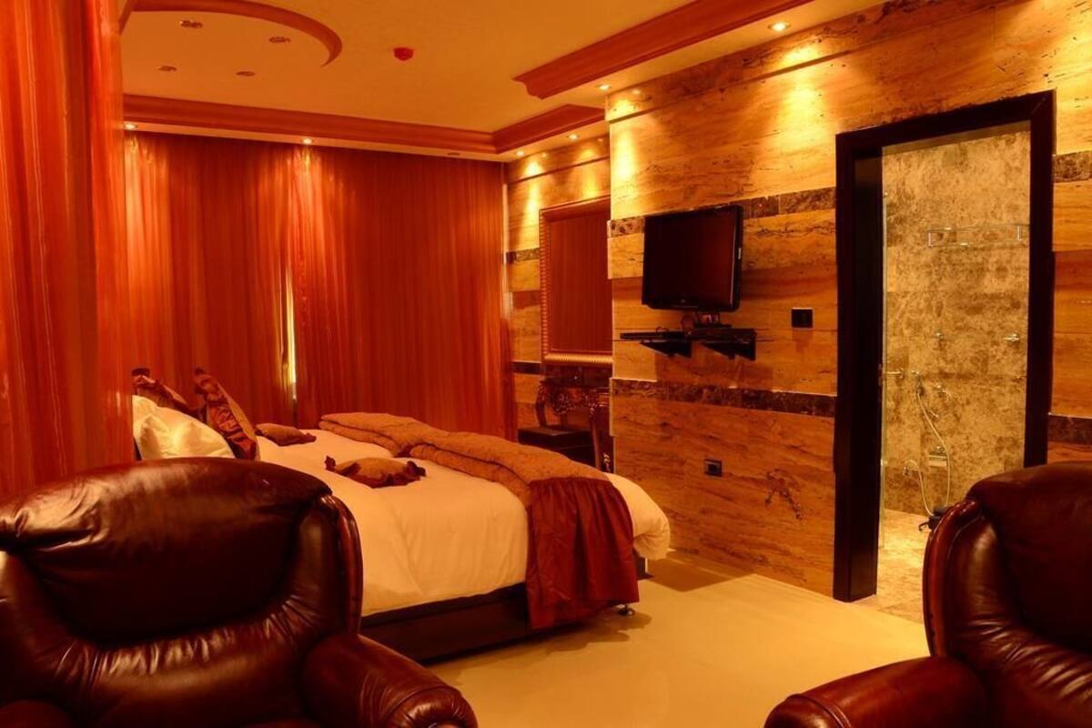 A bedroom with a bed, a TV mounted on the wall, and a door leading to a bathroom.