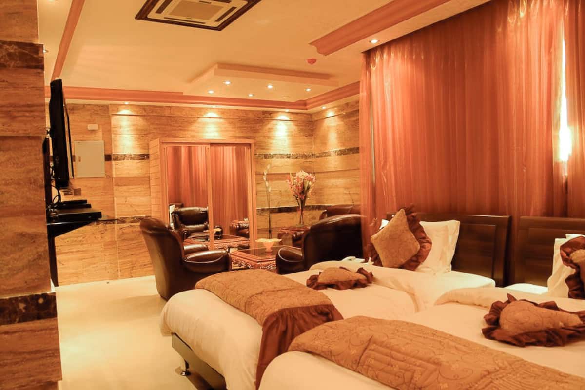 A hotel room with a large bed, a sitting area with a chair and a table, and a television on a stand.