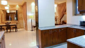 A modern kitchen with wooden cabinets, a granite countertop, and a built-in microwave. - Jad Hotel Suites (Amman)