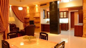 A dining area with a marble table, chairs, and a decorative glass centerpiece. - Jad Hotel Suites (Amman)