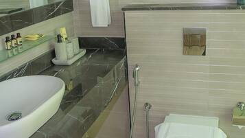 A modern bathroom with a large sink, a mirror, a toilet, and a shower.