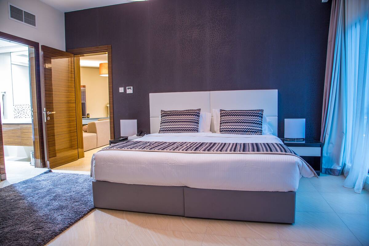 Une chambre d’hôtel moderne, dotée d’un grand lit, de tables de chevet et offrant une vue sur l’extérieur.