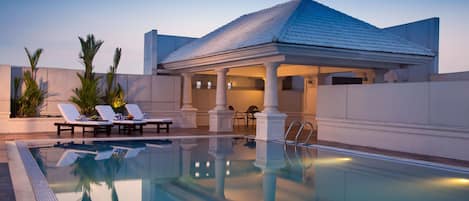 A pool area with lounge chairs and a covered seating area.