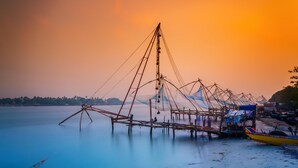 A fishing net structure extending into calm water, with a small boat docked nearby. - Radisson Blu Kochi (Kanayannur)
