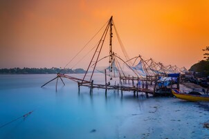 A fishing net structure extending into calm water, with a small boat docked nearby.