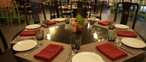 Mesa de comedor para seis personas, con servilletas rojas, cubiertos y una pieza central.